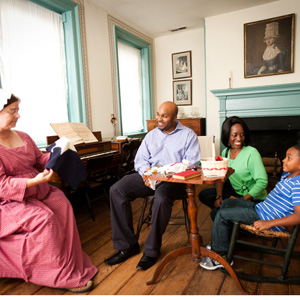 Three Visitors listening to costumed presenter in Flag House