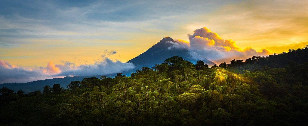 Arenal Volcano at Sunrise...A rare sight at the perfect 15 second window to capture sunrise in all of it's glory. Light glistens off the clouds and the mountain and the jungle.