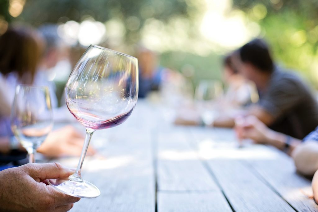 hand holding mostly empty wine glass at picnic table