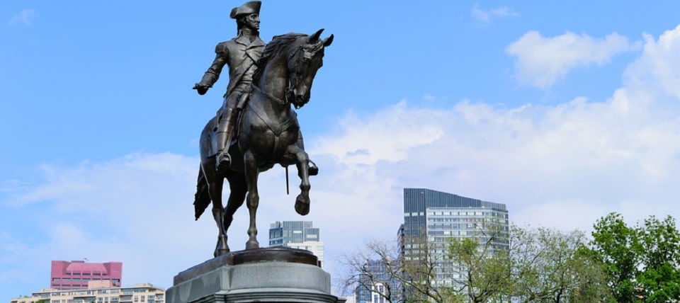 George Washington statue as the famous landmark in Boston Common Park with city skyline and skyscrapers.