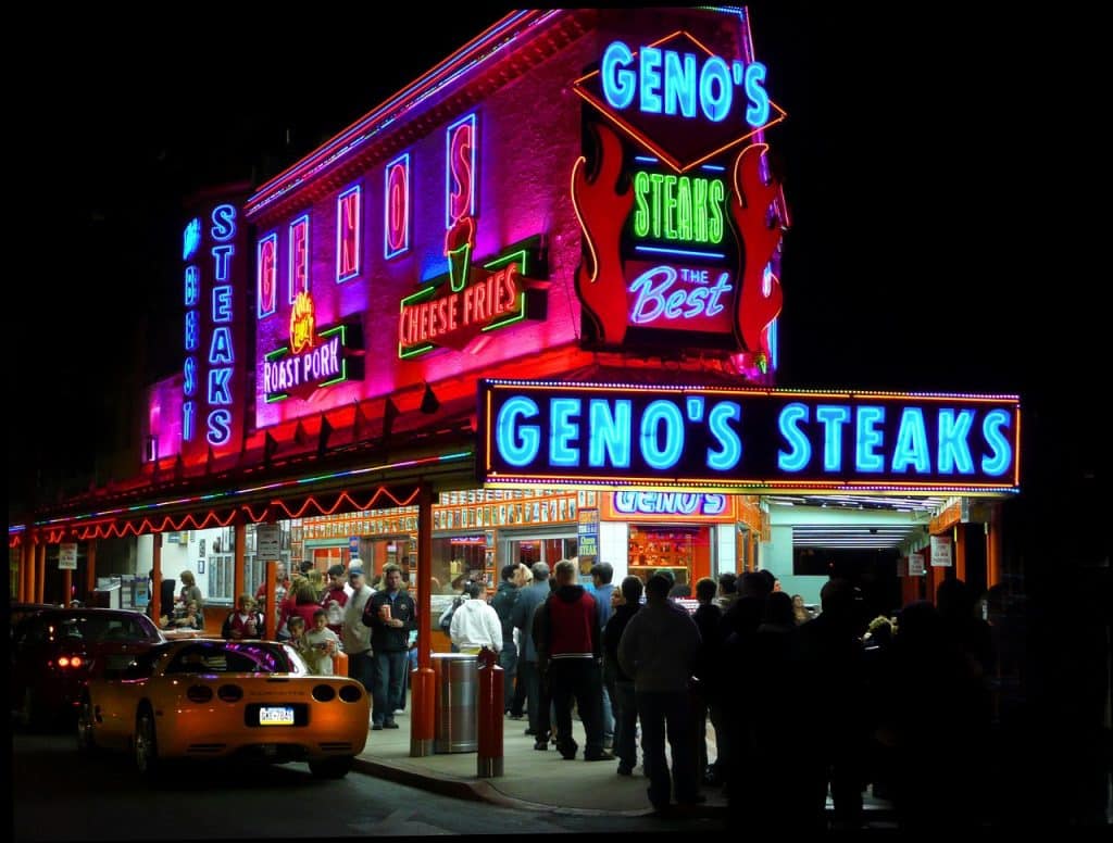Geno's Steaks with long line and neon signs lit up at night