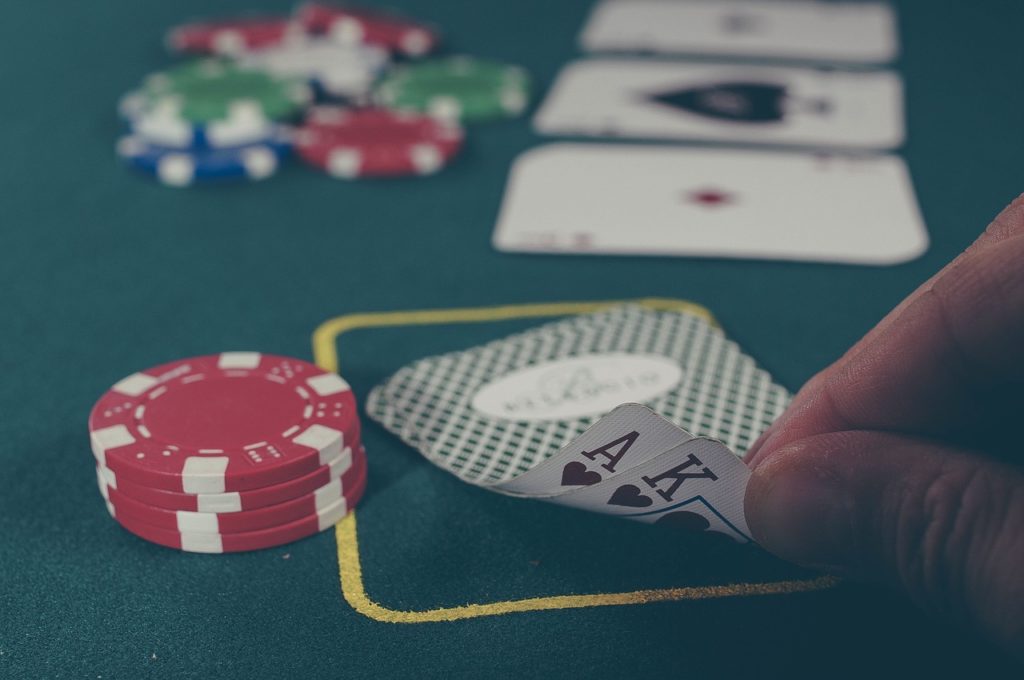 Poker player lifting up cards to reveal Ace and King of hearts