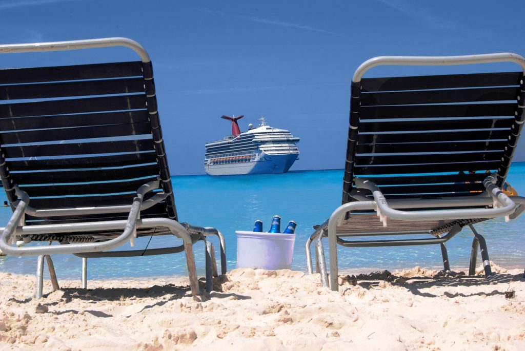 Carnival Cruise Ship seen from beach with lounge chairs and drinks in bucket in sand