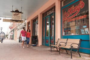 Two people walking by LaKings Confectionery Exterior. large traditional soda shop style signs